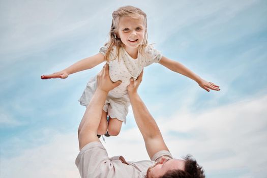 Adorable little blonde girl playing outside with her father against a clear blue sky. Cute female child smiling and bonding with her dad outdoors during summer. Having so much fun with his daughter.