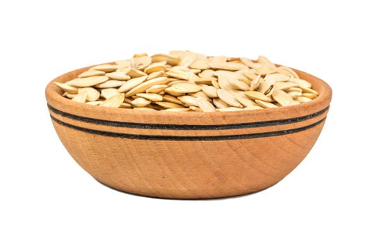 Roasted pumpkin seeds in a wooden bowl on a white background