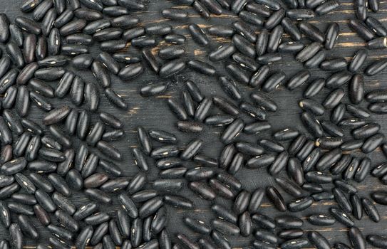 Scattered black beans on wooden background, top view