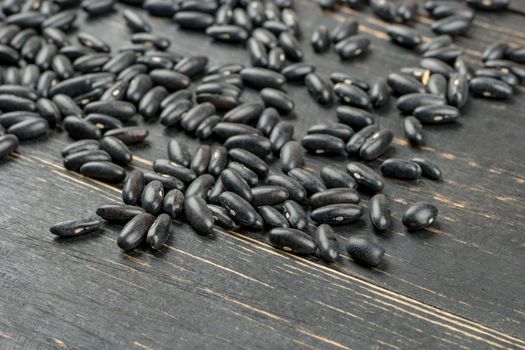 Scattered black beans on wooden background closeup
