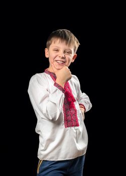 Laughing boy in traditional Ukrainian clothes on a black background