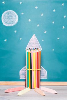 vertical photo of a rocket made with crayons and drawn on a blackboard, concept of imagination and back to school