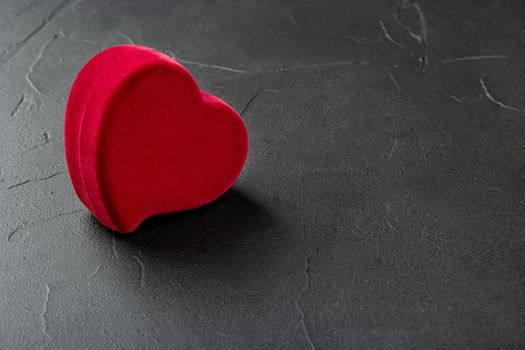 Red box for rings in the shape of a heart on a concrete background