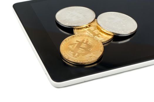 Silver and gold coins of bitcoin on the tablet closeup