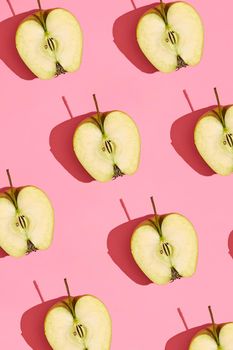 Food design. Top view of colorful fruit pattern of fresh cutted apple halves with pits on coral pink pastel background. Mock up, flat lay style.