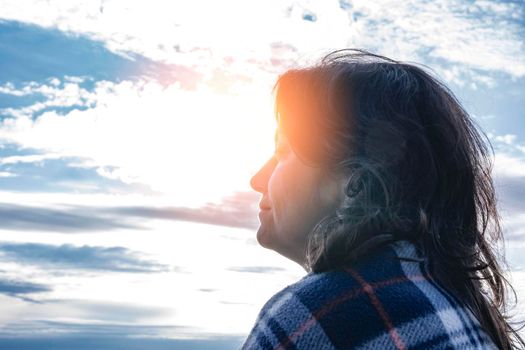 a pretty, long-haired, middle-aged brunette woman walks by the sea in the setting sun. harmony, dreams. vacation by the sea