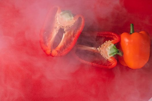 SWEET, fresh RED PEPPER ON A RED BACKGROUND, cut in half, thick smoke around. proper nutrition. fresh vegetables