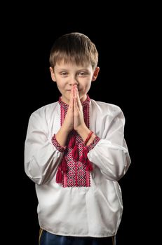 Praying boy in traditional Ukrainian clothes on a black background