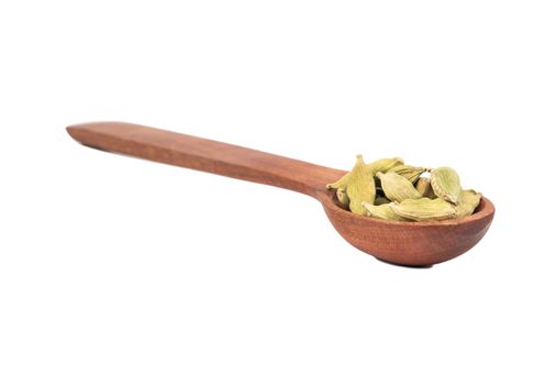 Green cardamom in wooden spoon isolated on white background