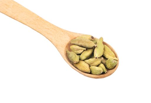 Wooden spoon with dry green cardamom closeup on white background