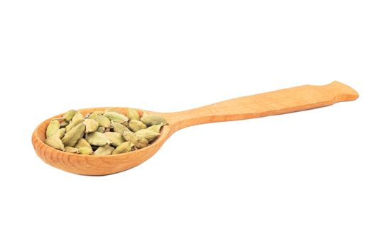 Dry cardamom in a large wooden spoon on a white background