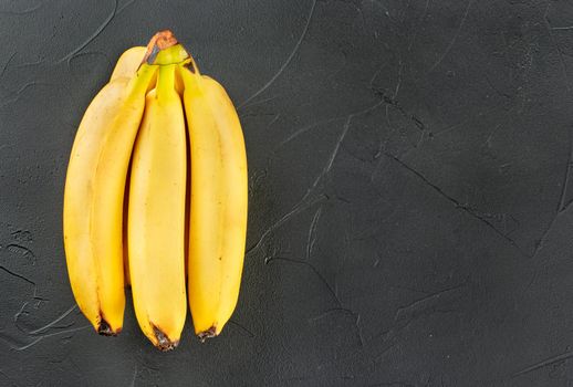 Branch of ripe bananas on an empty dark concrete background