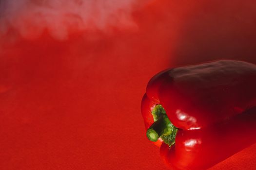 SWEET, fresh RED PEPPER ON A RED BACKGROUND WITH A LIGHT SMOKE