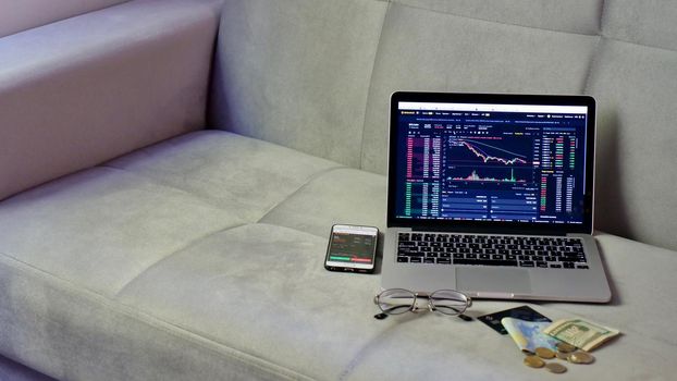 Laptop and phone to buy bitcoin on the Binance crypto exchange during the market crash. Trading, spot, staking. Workspace freelance flatlay