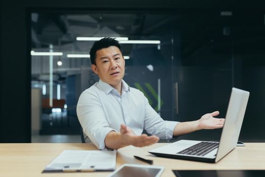 Portrait of Asian businessman man, disappointedly spreading hands and looking at camera, Korean owner manager working in modern office, not satisfied with work result.