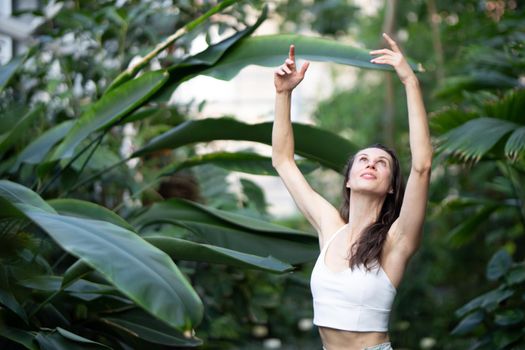 Female meditating and practicing yoga in tropical rainforest. Beautiful young woman practicing yoga outdoor with tropical forest in background