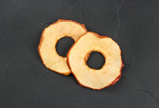 Two dry Apple chips on a dark concrete background, top view