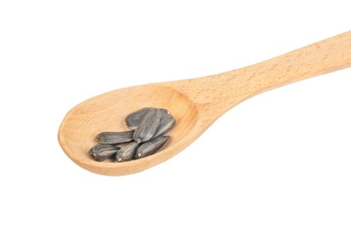 Sunflower seeds in a small wooden spoon on a white background closeup