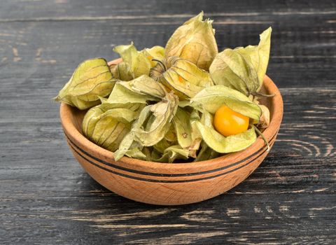 Bowl filled with fruit physalis in a peel on a table