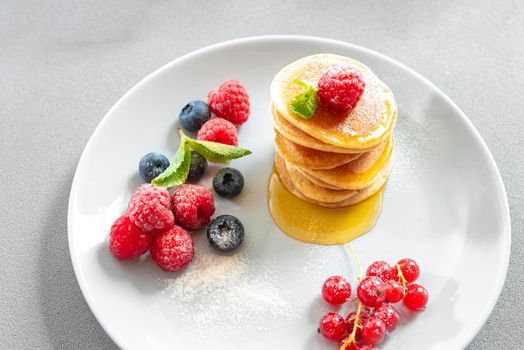 Food for breakfast healthy eating. Pancakes with honey. Homemade pancakes on a white background. European breakfast pancakes and berries. Pancakes without butter with berries. Food for vegetarians and for dieting. American Pancakes Mini. Top view