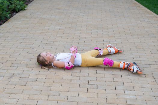 Little girl learns to roller skate and falls. View from above.