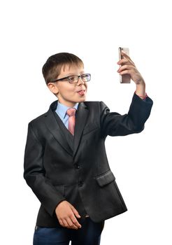 Schoolboy in suit makes selfie on phone and shows tongue