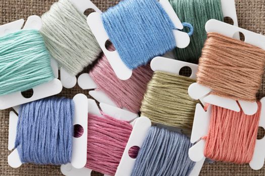 Embroidery floss on bobbins in pastel greens, blues and pinks.