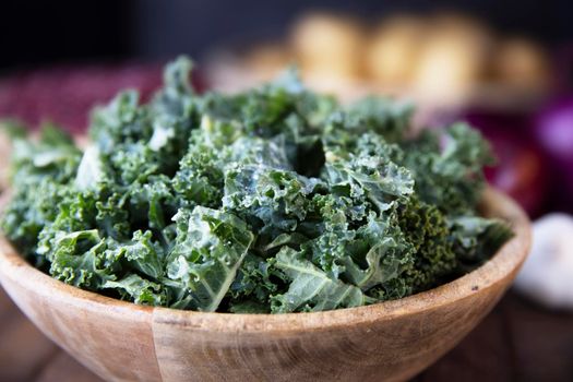 Close up of chopped fresh kale in wooden bowl.