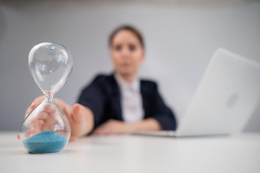 Business woman flipping an hourglass at her desk