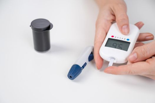 Woman measures blood sugar level with a glucometer