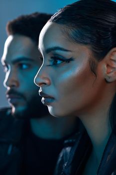 Conceptual shot of a stylish young man and woman posing in studio against a blue background.