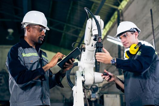Factory workers working with adept robotic arm in a workshop . Industry robot programming software for automated manufacturing technology .