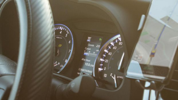 Illuminated speedometer dashboard and steering wheel of a modern car in a sun flare.