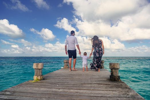 A man and a woman with a child walk on the pier by the sea. Mexico.