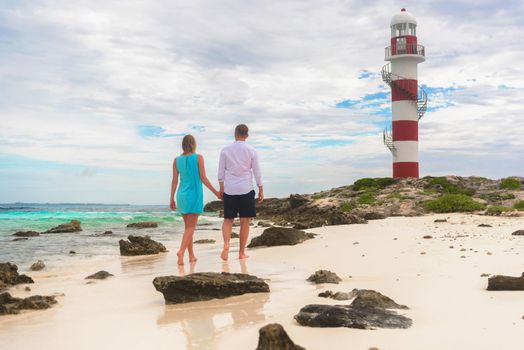 A man and a woman walk on the seashore.