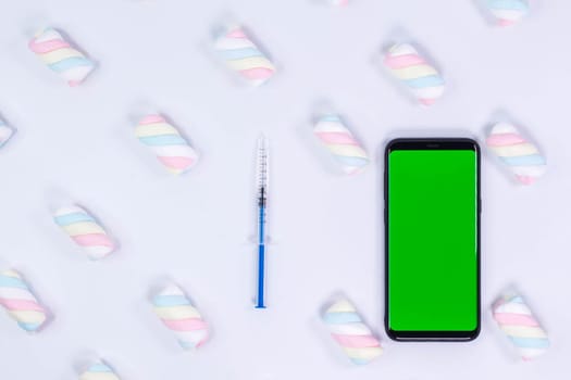 Phone mockup. Syringe with needle and black smartphone with blank screen. White background with twisted marshmallow pattern.