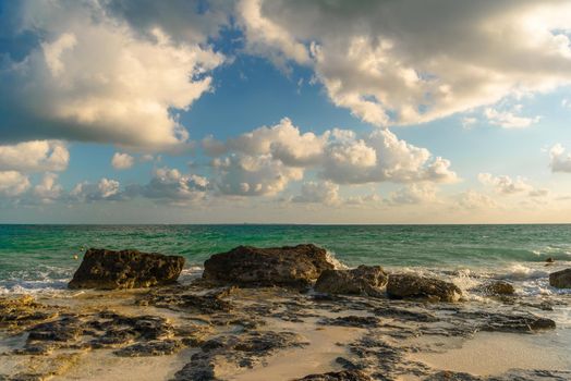 The coastline of the Caribbean Sea with white sand and rocks in Cancun.