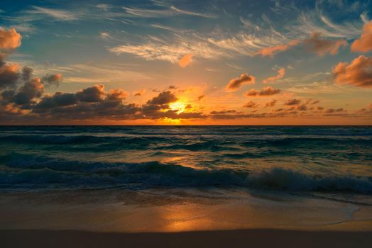 Sunset on the Caribbean Sea. The sun's rays make their way through the clouds.