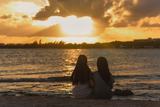 Silhouettes of two women against backdrop of the setting sun