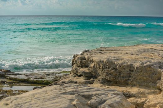 The coastline of the Caribbean Sea with white sand and rocks in Cancun.