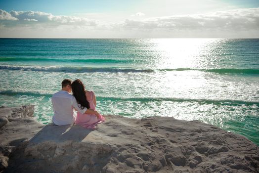 A man and a woman are sitting on the seashore.