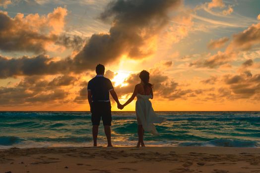 Silhouettes of men and women against the backdrop of the setting sun