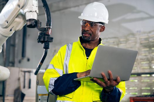 African American factory worker working with adept robotic arm in a workshop . Industry robot programming software for automated manufacturing technology .