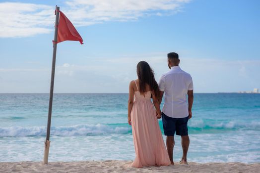 A man and a woman walk on the seashore.