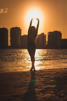 The silhouette of a woman on the beach and against the backdrop of the city sunset.