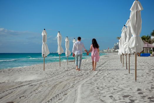 A man and a woman walk on the seashore.