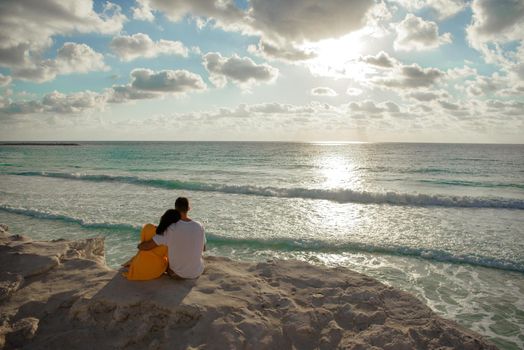 A man and a woman are sitting on the seashore.