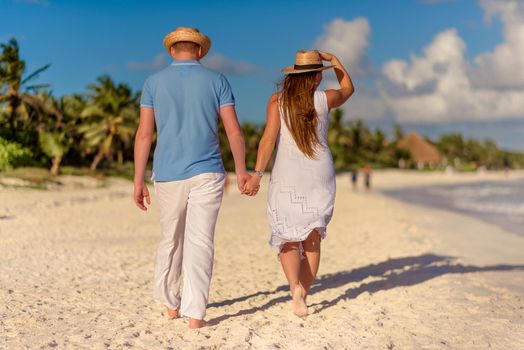 A man and a woman walk on the seashore.