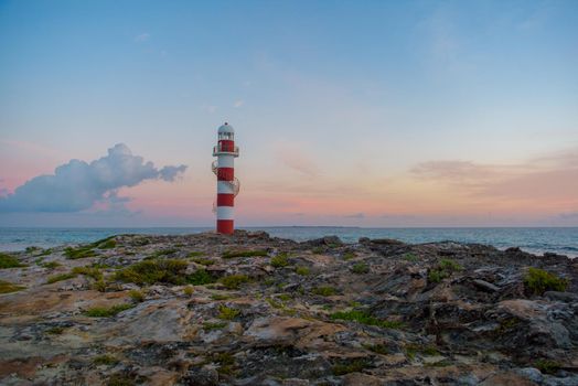 Lighthouse on a rocky shore in Cancun. Clear sky and blue sea.