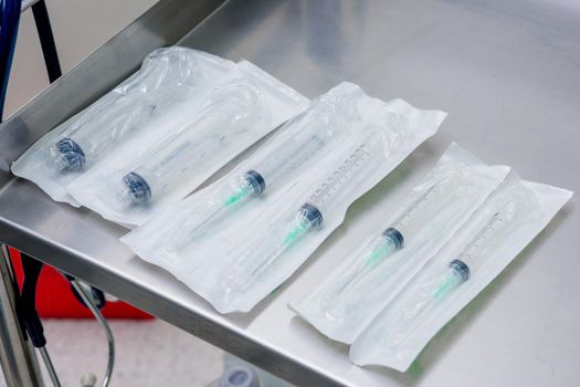 Syringes in packaging on a table in the operating room.